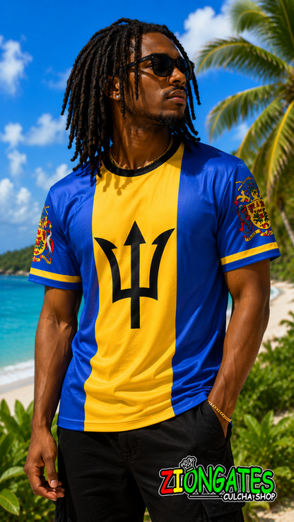 A man wearing a barbados athletic t-shirt with a blue and yellow vertical split, featuring the black trident emblem in the center. He is standing on a tropical beach with palm trees and blue ocean water in the background.