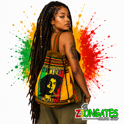 A woman with long black dreadlocks models a yellow Rasta-themed tote bag featuring Bob Marley artwork and the words 'ONE LOVE', 'BOB MARLY', The background is white with large red, yellow, and green paint splatters, and a 'ZIONGATES CULCHA SHOP' logo is in the bottom right corner.